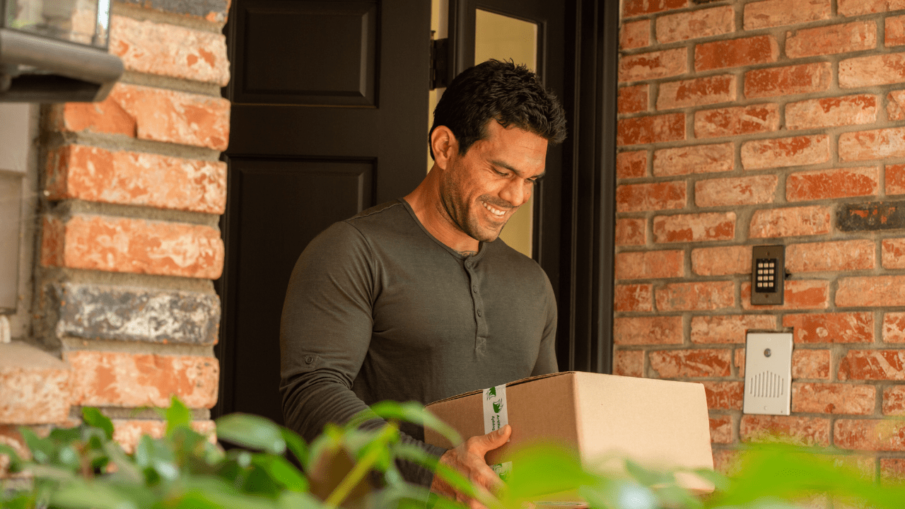 a homeowner smiling as he receives free artificial grass supply samples